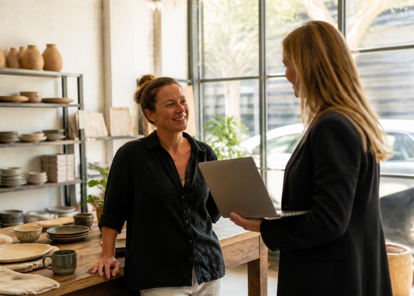 Business owner in her showroom talking through a plan with a consultant holding a laptop